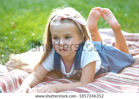 Portrait of pretty child girl resting outdoors in summer park.