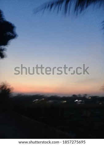 Blurred beautiful blue and orange sunset with tree silhouette. Shaky, noisy