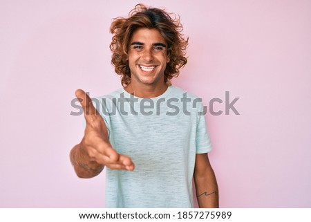 Young hispanic man wearing casual clothes smiling friendly offering handshake as greeting and welcoming. successful business. 