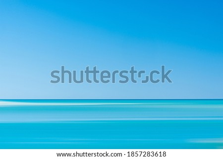 Motion blur of sea and sand bar inder clear sky