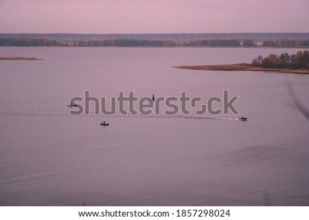 Beautiful autumn sunset river landscape. Boats and fishermen.