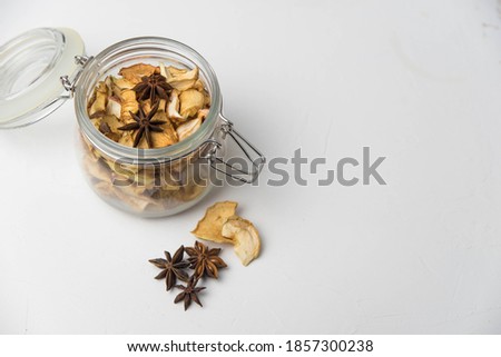 Homemade crispy sun dried organic apple slices. Close up of apple chips with spice in glass jar isolated on white background with copy space for text