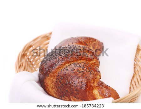 Image of croissant with poppy in a basket. Whole background