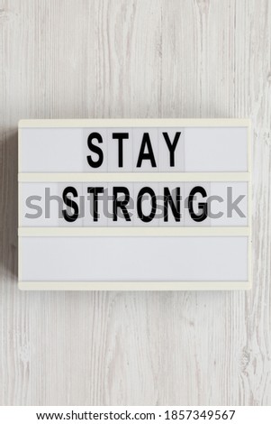 'Stay strong' on a lightbox on a white wooden background, top view. Flat lay, overhead, from above. 