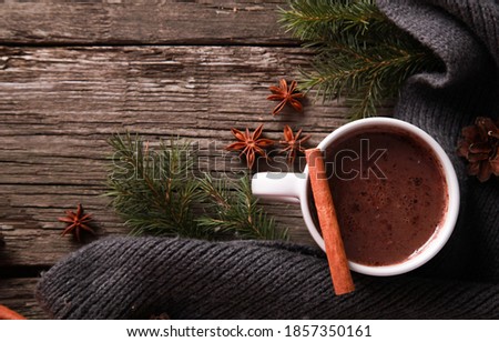 Mug of chocolate, spices, grey knitted scarf, fir tree branches, cones on rustic wooden table background. Winter drink and Christmas concept. Spicy cocoa, New Year, top view, copy space, closeup