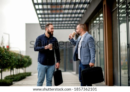 Two colleagues on coffee break in front of business building