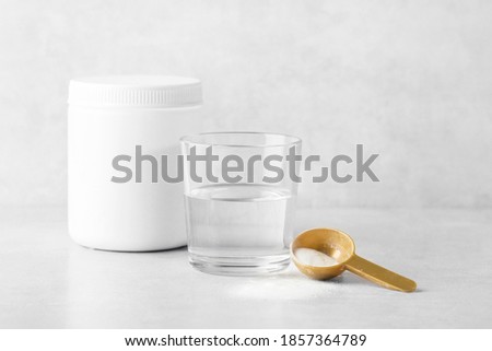 collagen powder with a glass of water on a gray background, jar, spoon, beauty and youth Royalty-Free Stock Photo #1857364789