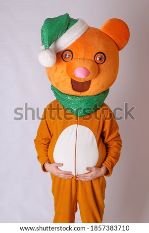 Orange costume growth bear. Toy bear in a Christmas hat. New Year's costumes for children and adults