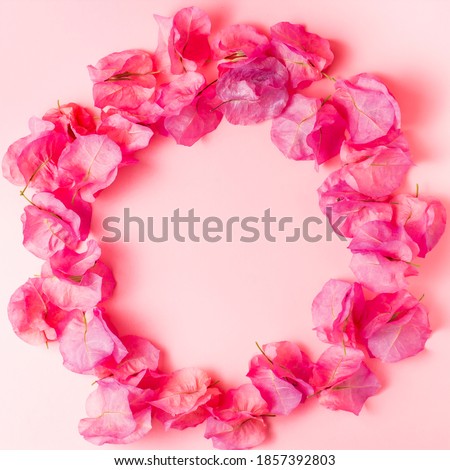 Round frame of bougainvillea buds on a light pink background close-up. Copy space, top view, flat lay.