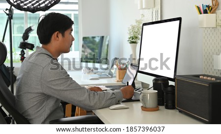 Side view of graphic designer or photographer is using  graphic table retouching a photo at his workspace.