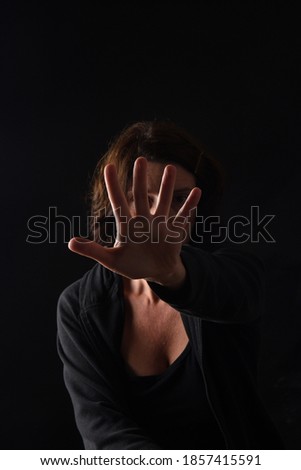 dark portrait of a woman with open palm on black bakcground