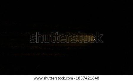  top view of the night road along which a lonely car drives in the middle of the forest and shines with headlights