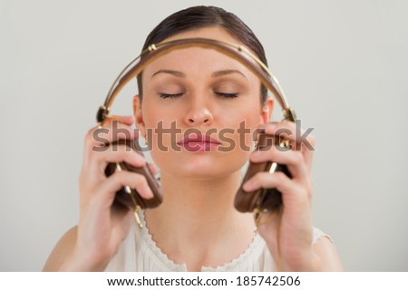 Woman with headphones listening music. Music teenager girl dancing against gray