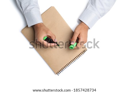 Man with highlighter and notepad on white background, top view. Closeup of hands