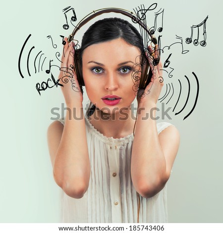 Girl with headphones on the grey background and musical symbols flying from her headphones