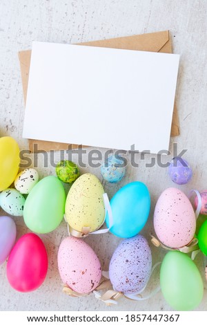 Easter scene with colored eggs border, flat lay on white wooden background, copy space on blank card