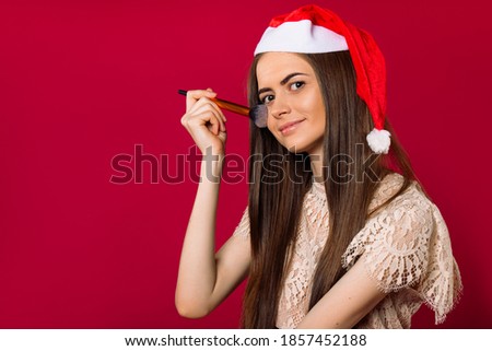 Girl in Claus hat, powders face, on a pink background with empty side space.