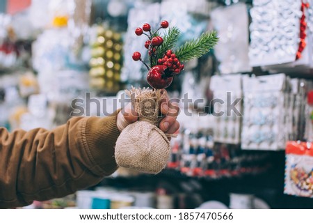 A man in a supermarket holds decorative holiday decorations in his hands