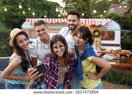 Happy friends taking selfie near trailer. Camping season