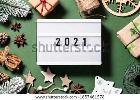 2021 on the lightbox with assortment of natural Eco friendly festive decorations on dark green background. New Year concept.