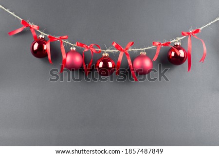 thread with red christmas balls and red bows on black background