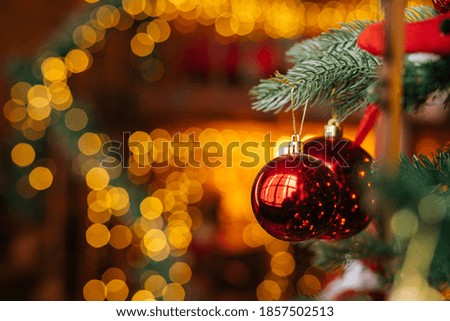Close-up view of red beautiful ball on Christmas tree, background lot of blurry lights. Xmas tree baubles and tinsel lights blinking at New Year Eve on blur bokeh background.