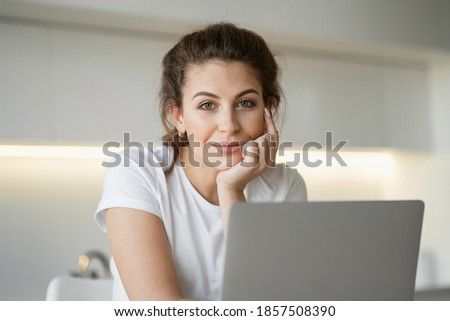 makes home purchases of food products from a store near the house. Place to copy. A brunette woman is engaged in online shopping in the website app on a laptop computer gadget. looking at the camera Royalty-Free Stock Photo #1857508390