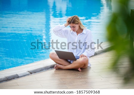 Beautiful woman working with laptop by the pool. Freelance remote work