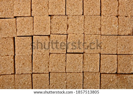 Close up background texture pattern of brown cane sugar cubes arranged