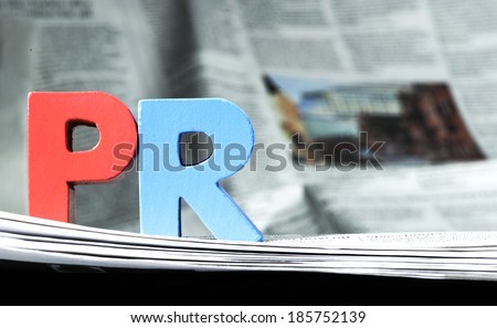 Word PR on newspaper. Wooden letters Royalty-Free Stock Photo #185752139