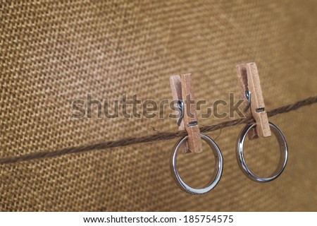 couple rings hanging with wooden paper clip on rope with old fabric background