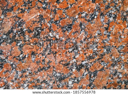 Grunge background from red granite natural stone texture. Polished surface, copy space.