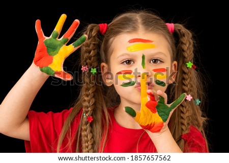 A small beautiful girl with pigtails holds her finger near her lips.
