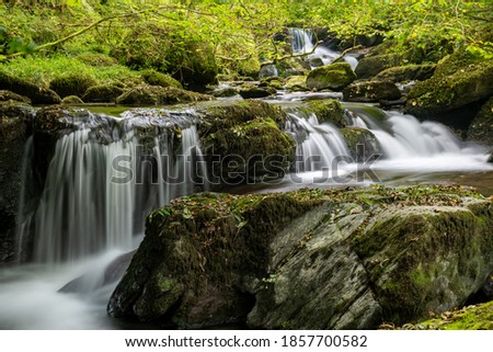 Long exposure of a waterfall on the Hoar Oak Water river flowing through the woods at Watersmeet in Exmoor National Park