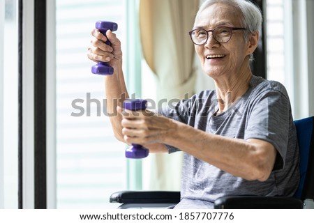Strong asian senior woman working out with heavy dumbbells,lifting dumbbell weights for strength training,fitness elderly people doing exercise while sit in wheelchair,health care,healthy lifestyle Royalty-Free Stock Photo #1857707776
