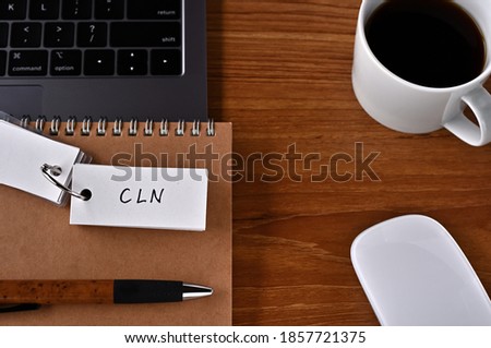 On the desk there is a laptop, a cup of coffee, and a word book with the word CLN written on it. It was an abbreviation for the financial term credit linked note.