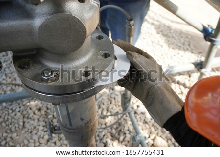 Worker hands inserting the Gasket sheet between slots of flange on stainless steel pipe is part of new demineralized water process in oil & gas plant or chemical industrial. Royalty-Free Stock Photo #1857755431
