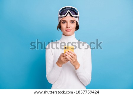 Photo of brown bob haired woman hold phone wear ski gear serious mood isolated on blue color background