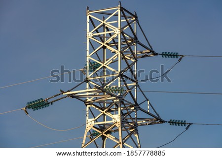 Close up low angle shot of high voltage electric tower and power lines in the city. Blue sky background. Barnaul, Siberia, Russia.