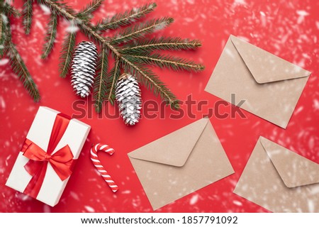 Gift box for Christmas celebration with festive decorations on the red background with copy space. Envelopes for letters