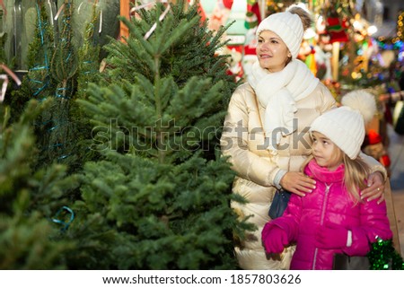 Mother and daughter staying at market among Christmas trees. High quality photo