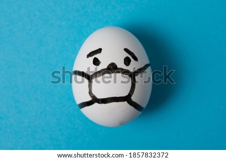 An egg with a masked face. Isolate on a blue background. Covid 19 and quarantine concept.
