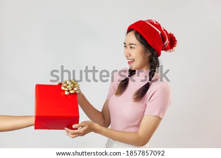Young asian woman portrait weared red wool hat pink t-shirt taking gift red box on the white background.
