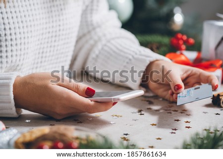 Woman shopping Christmas gifts online with a credit card and mobile phone