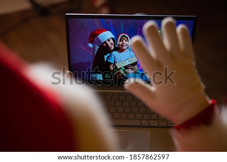 Happy mom and son talking to santa claus by video chat on a laptop. Woman and boy remotely wishes Merry Christmas