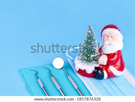 Merry Christmas And Happy New Year From Dentist Set of Dental Tools And Santa Claus On Blue Background.