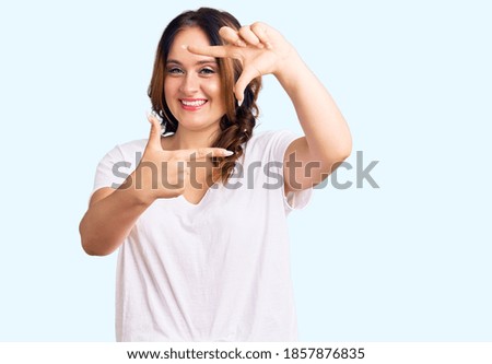 Young beautiful caucasian woman wearing casual white tshirt smiling making frame with hands and fingers with happy face. creativity and photography concept. 