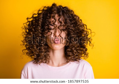 Headshot of girl with curly hairstyle wearing t-shirt send air kiss pouted lips isolated on vivid yellow color background Royalty-Free Stock Photo #1857897535