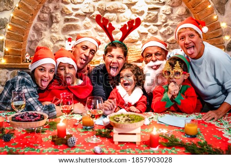 Funny selfie pic of multi generation big family with santa hats having fun at Christmas fest house party - Winter holiday xmas concept with grand parents and children eating together - Vivid filter