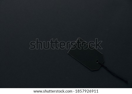 Blank black cardboard paper label or price tag with cord isolated on dark background. Black Friday, Shopping, sale and marketing concept. Top view, flat lay, copy space. .